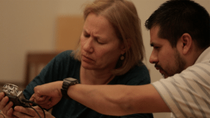 Debby Bussel, a blonde, white woman, examines a recorder as Roberto Nava points to various features at Storymakers training, March 2016. Video still by Ian McClerin.